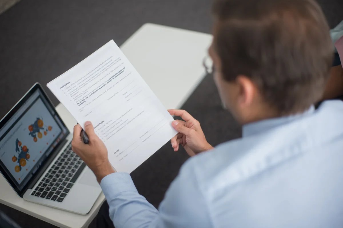 Investor reviewing financing documents beside a laptop